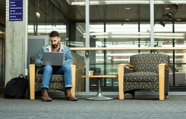 Student Sitting And Using A Laptop In The HUB